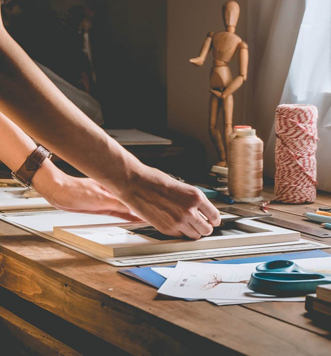 Beautiful woman hand crafting book at the tabletop with stationery. Stylish craftswoman with stationery work at his hipster workstation.