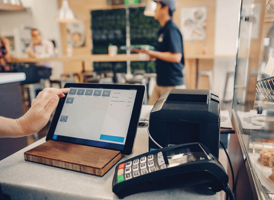 Closeup shot of caucasian cashier hands. Seller using touch pad for accepting client customer payment. Small business of coffee shop cafeteria.